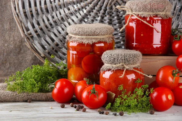 Smakelijke ingeblikte en verse tomaten op houten tafel — Stockfoto