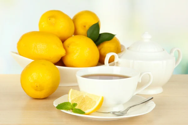 Filiżanka herbaty z cytryną na stole na jasnym tle — Zdjęcie stockowe