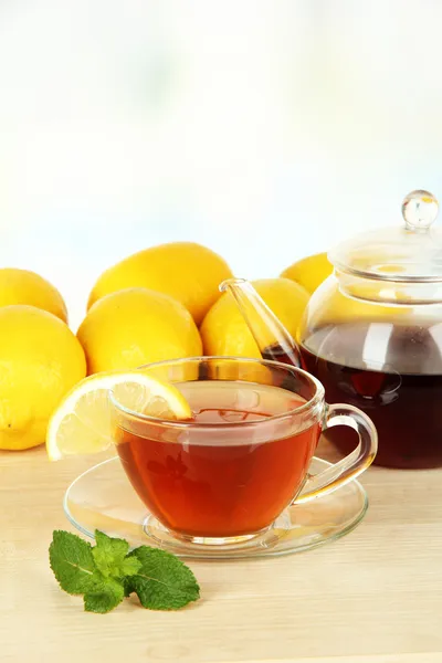 Filiżanka herbaty z cytryną na stole na jasnym tle — Zdjęcie stockowe