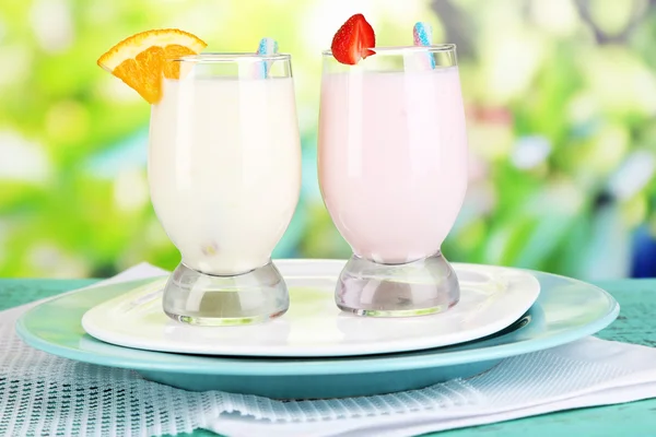 Deliciosos batidos de leche con naranja y fresas sobre mesa de madera sobre fondo natural —  Fotos de Stock