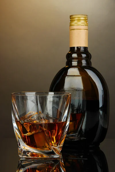 Glass of liquor with bottle, on dark background — Stock Photo, Image