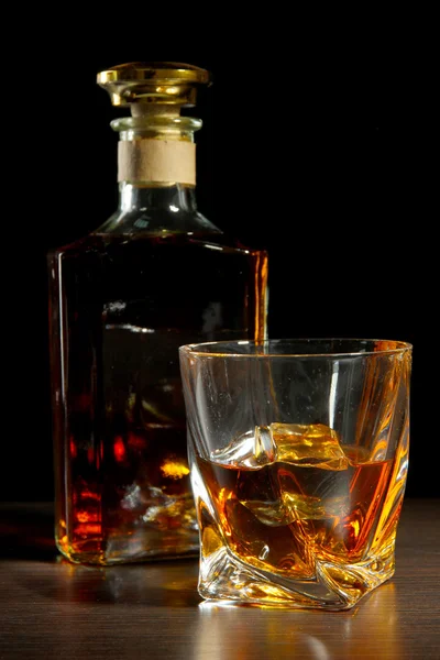 Glass of whiskey with bottle, on dark background — Stock Photo, Image