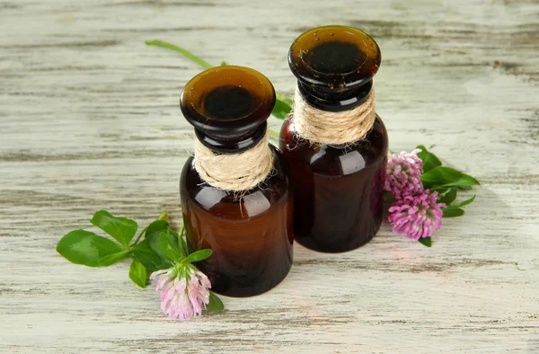 Medizinflaschen mit Kleeblumen auf Holztisch — Stockfoto