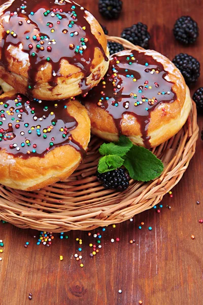 Вкусные пончики с шоколадом и ягодами на деревянном столе — стоковое фото