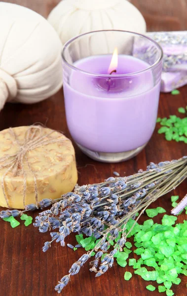 Asetelma laventeli kynttilä, saippua, hieronta pallot, pullot, saippua ja tuore laventeli, puinen pöytä taustalla — kuvapankkivalokuva