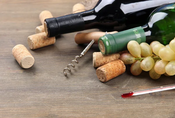 Bottles of wine, grapes and corks on wooden background — Stock Photo, Image