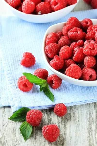 Ripe sweet raspberries in bowls on wooden background — Stock Photo, Image