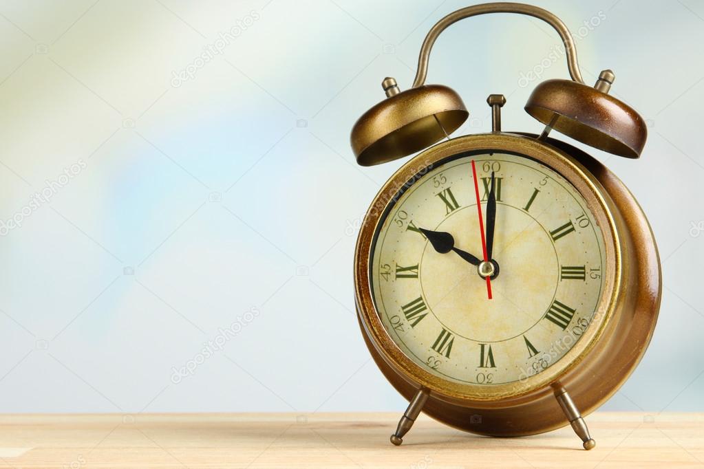 Old alarm clock on bright background
