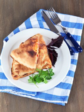 Pizza calzones tabakta üzerine peçete ahşap masa üzerinde