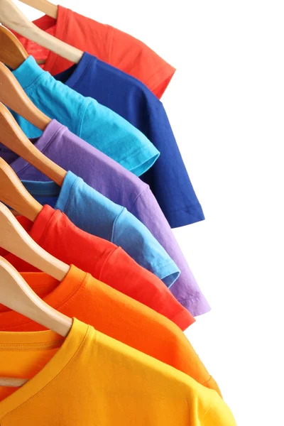 Lots of T-shirts on hangers isolated on white — Stock Photo, Image