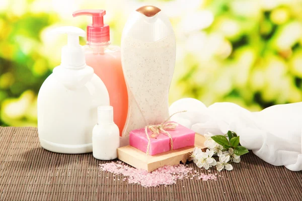 Cosmetics bottles and natural handmade soap on green background — Stock Photo, Image