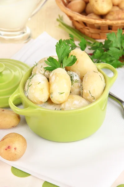 Tender young potatoes with sour cream and herbs in pan on wooden table close-up — Stock Photo, Image