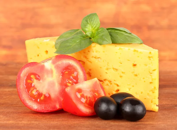 Sýrem, bazalkou a zelenina na dřevěné pozadí — Stock fotografie