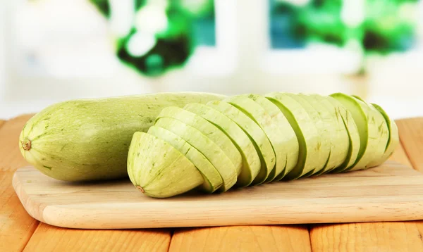 Fresh marrows on cutting board, on wooden table, on bright background — Stock Photo, Image