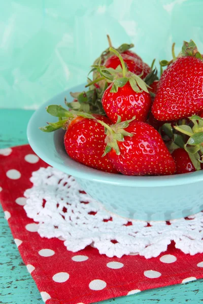 Strawberries in plate on napkin on blue background — Stock Photo, Image