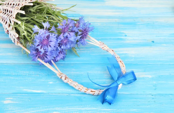 Beautiful bouquet of cornflowers in basket on blue background — Stock Photo, Image