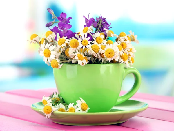 明るい背景上のカップにカモミールの花の花束 — ストック写真