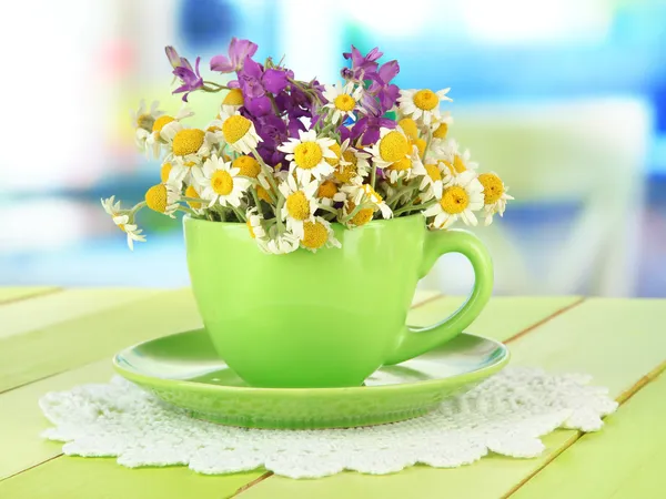 Bouquet of chamomile flowers in cup, on bright background — Stock Photo, Image