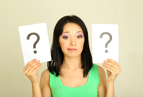 Woman with question marks on grey background — Stock Photo, Image