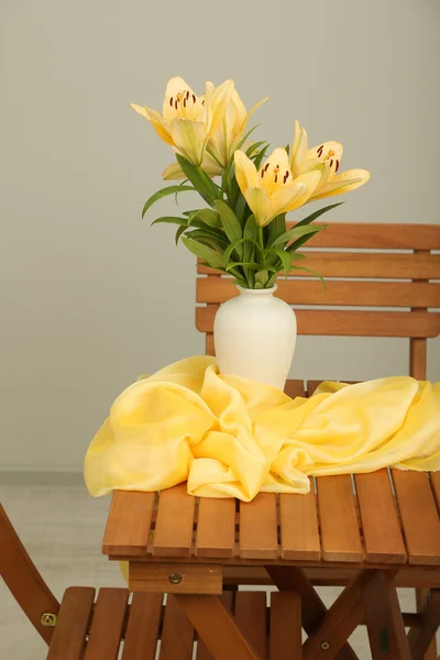 Hermosos lirios naranjas en jarrón sobre mesa de madera —  Fotos de Stock