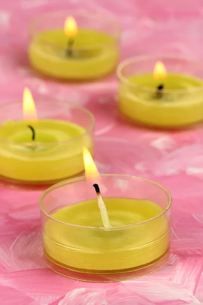 Lighted candles with beads on pink background — Stock Photo, Image