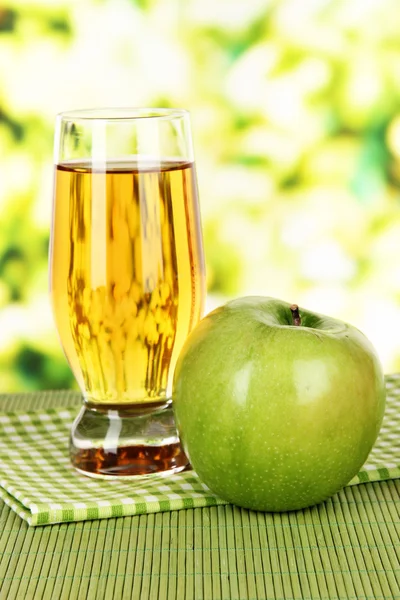 Vaso de zumo de manzana fresco sobre la mesa sobre fondo brillante — Foto de Stock