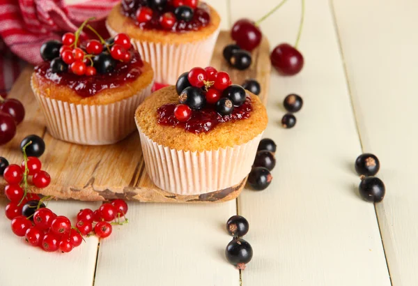 Smakelijke muffins met bessen op witte houten tafel — Stockfoto