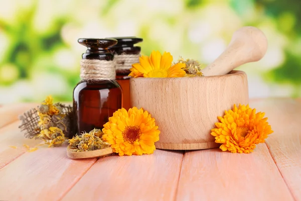 Medicine bottles and calendula flowers on wooden table — Stock Photo, Image