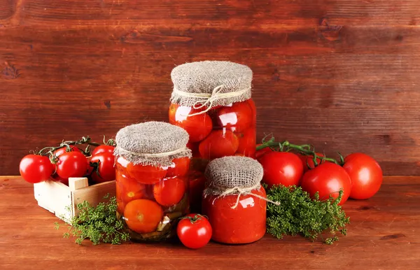 Sabrosos tomates enlatados y frescos sobre mesa de madera — Foto de Stock