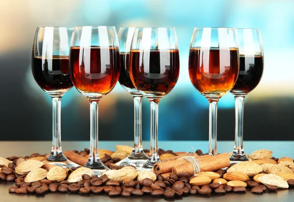Glasses of liquors with almonds and coffee grains, on bright background — Stock Photo, Image