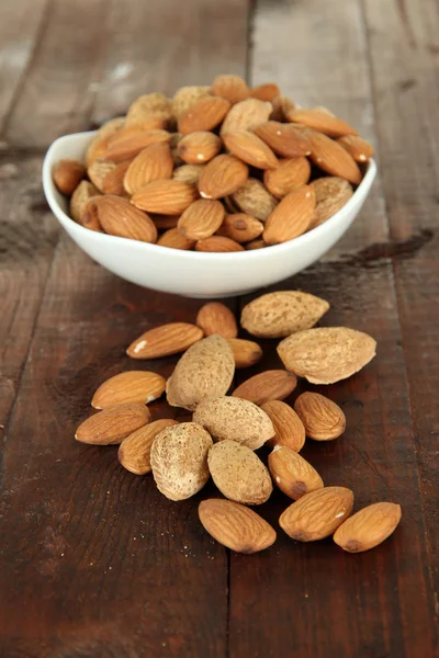 Almond in bowl, on wooden background — Stock Photo, Image