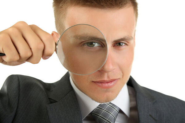 Young businessman looking through magnifying glass isolated on white