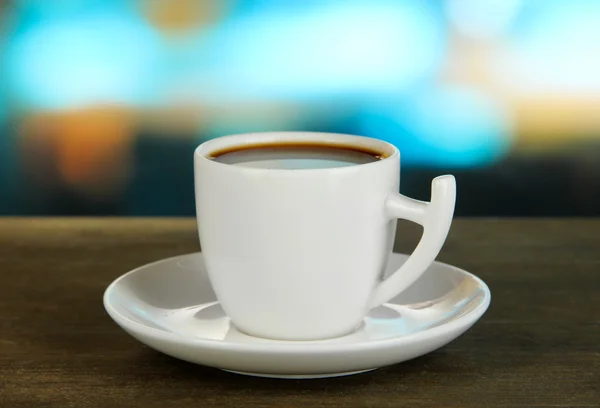 Xícara de café na mesa de madeira no fundo brilhante — Fotografia de Stock