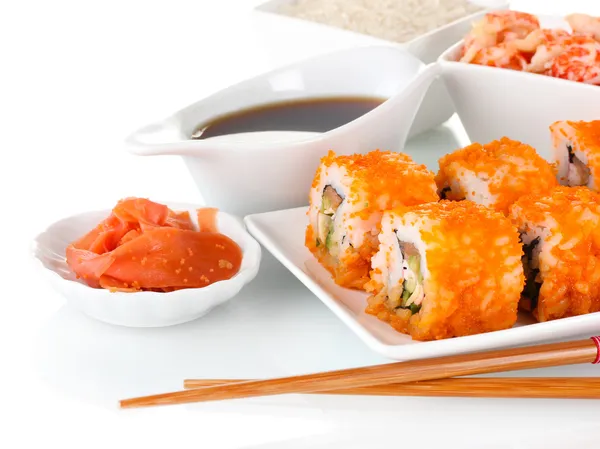 Вкусные суши на тарелке, палочки, соевый соус, рыба и креветки изолированы на белом — стоковое фото