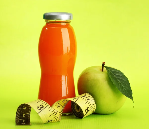 Flasche Saft, Apfel und Maßband, auf grünem Hintergrund — Stockfoto