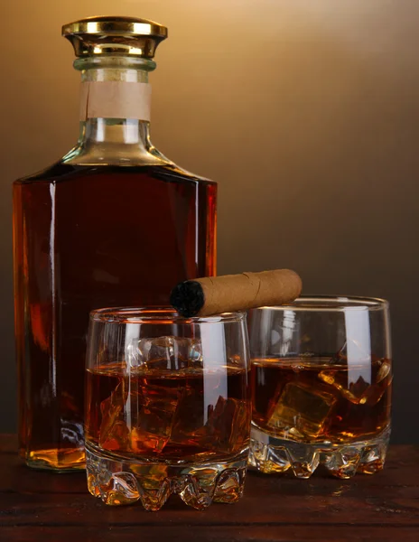 Brandy with ice on wooden table on brown background — Stock Photo, Image