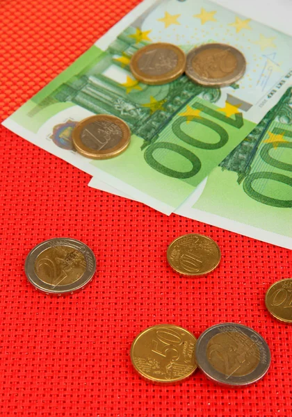 Euro banknotes and euro cents on red background — Stock Photo, Image