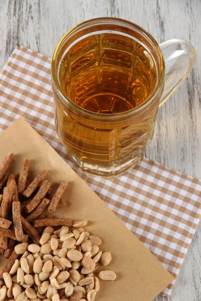Beer in glass crunches, and nuts on napkin on wooden table — Stock Photo, Image