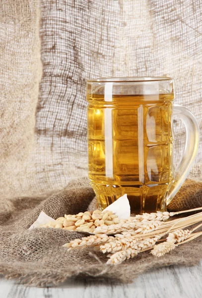 Pivo ve sklenici a ořechy na pytlování na dřevěný stůl — Stock fotografie