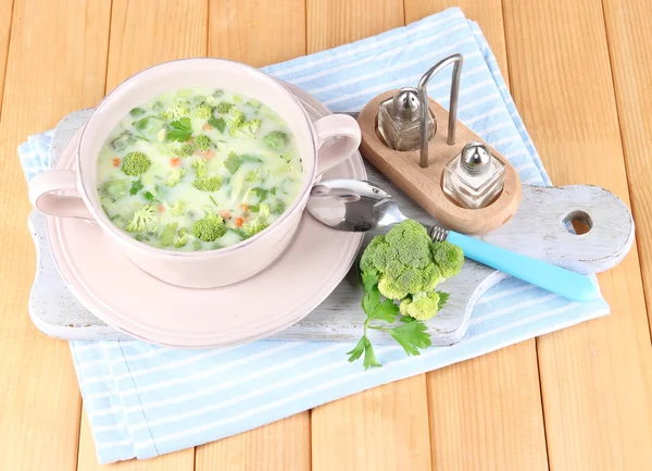 Cabbage soup in plate on napkin on board for cutting on wooden table — Stock Photo, Image