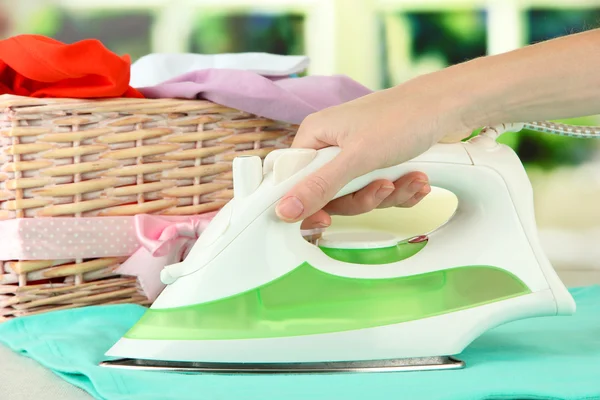Woman's hand ironing clothes, on bright background — Stock Photo, Image