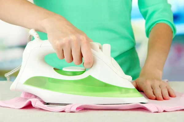 Woman's hand ironing clothes, on bright background — Stock Photo, Image