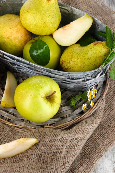 Pears in basket on braided tray on burlap on wooden table — Stock Photo, Image