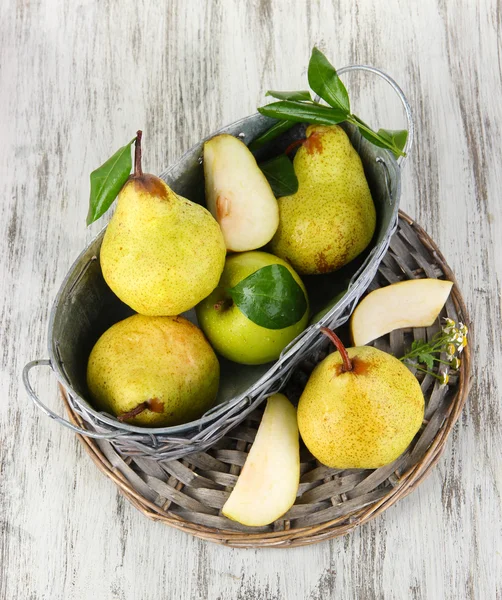 Pears in basket on braided tray on wooden table — Stock Photo, Image