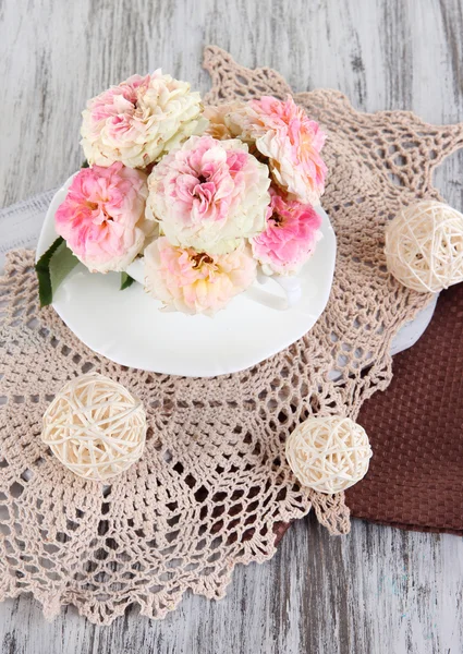 Rosen in Tasse auf Servietten auf Holzgrund — Stockfoto