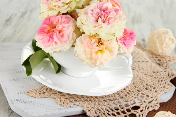 Rosas en taza sobre servilletas sobre fondo de madera —  Fotos de Stock