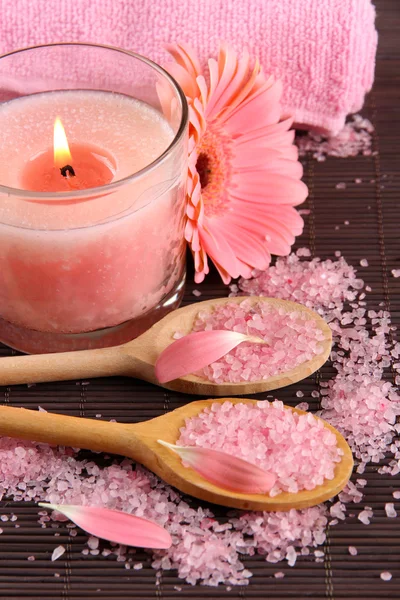 Krásná růžová svíčka s kytičkou a ručník na bambusové rohoži — Stock fotografie