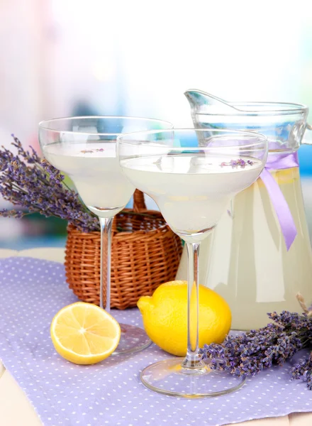 Limonade à la lavande dans une cruche en verre et des verres à cocktail, sur fond lumineux — Photo