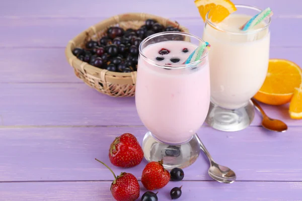 Delicious milk shakes with orange and blackberry on wooden table close-up — Stock Photo, Image