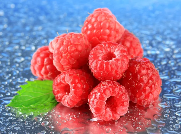Ripe sweet raspberries with drops, on blue background — Stock Photo, Image